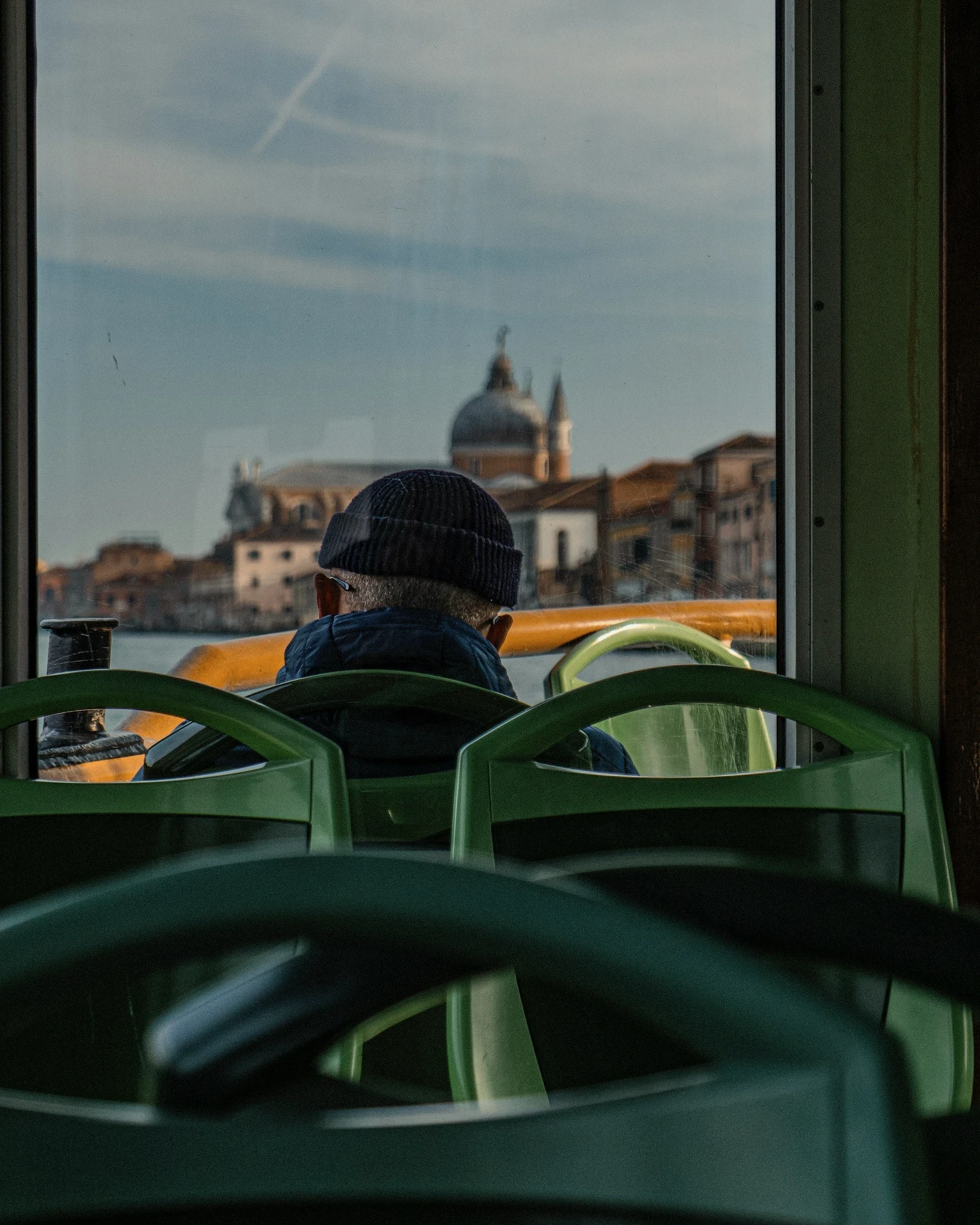 A traveller looking through a train window at a domed European city