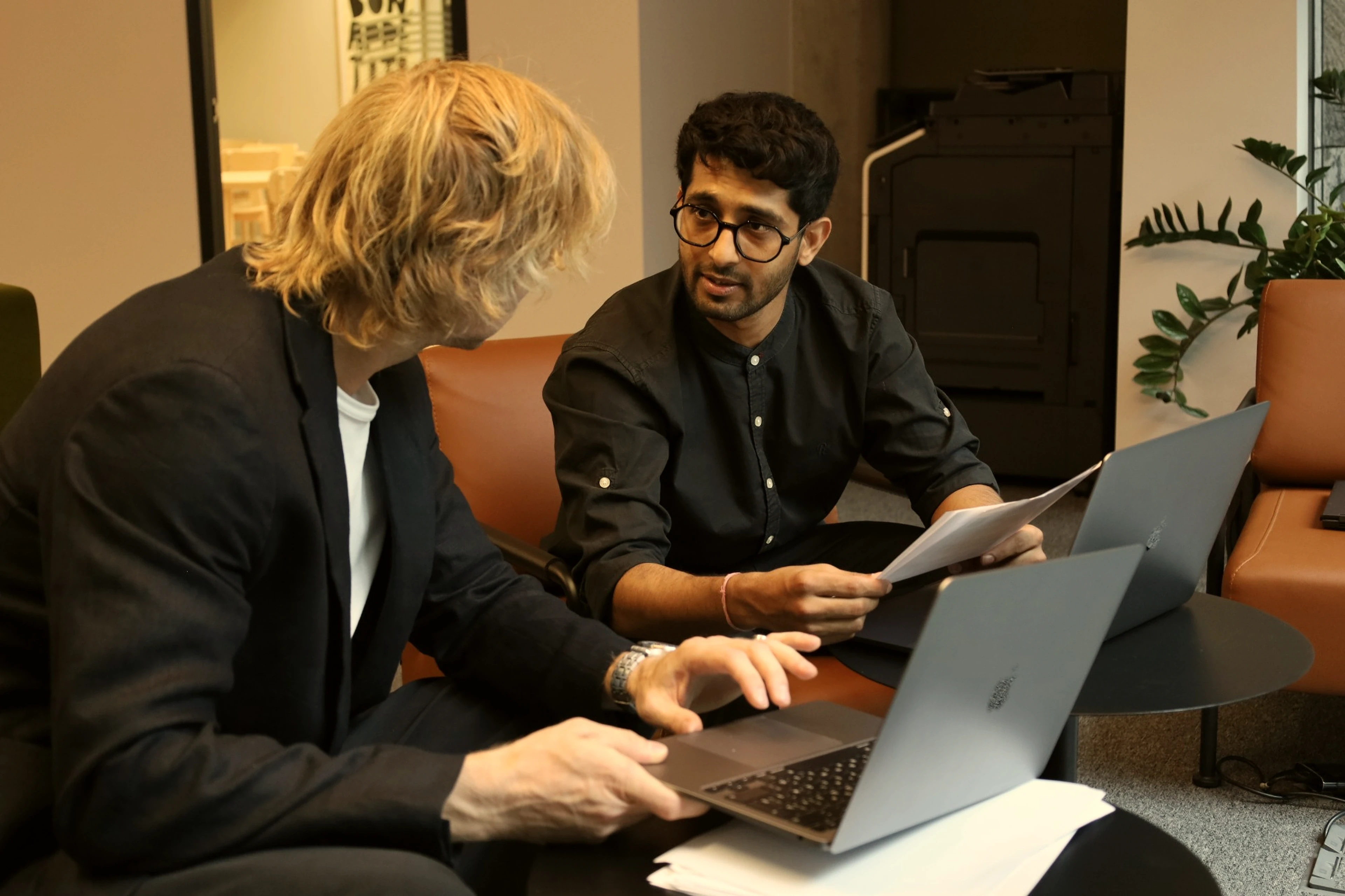 Two people going through documents together at laptops