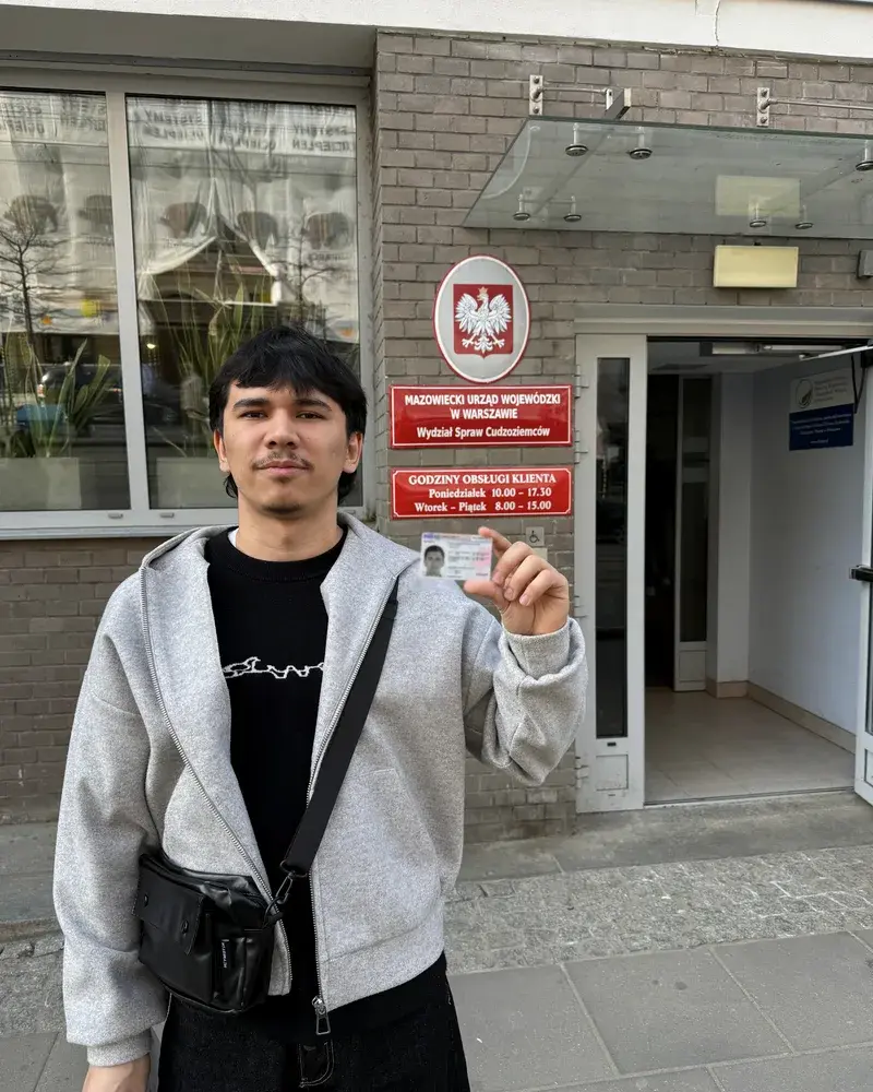 A client holding a new Polish residence card outside the immigration office in Warsaw