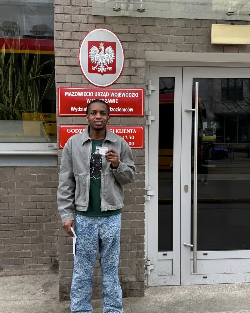A client holding a new Polish residence card outside the immigration office in Warsaw