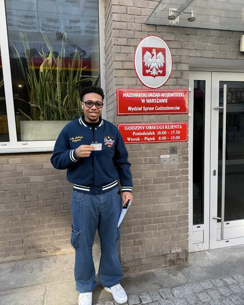 A client holding a new Polish residence card outside the immigration office in Warsaw