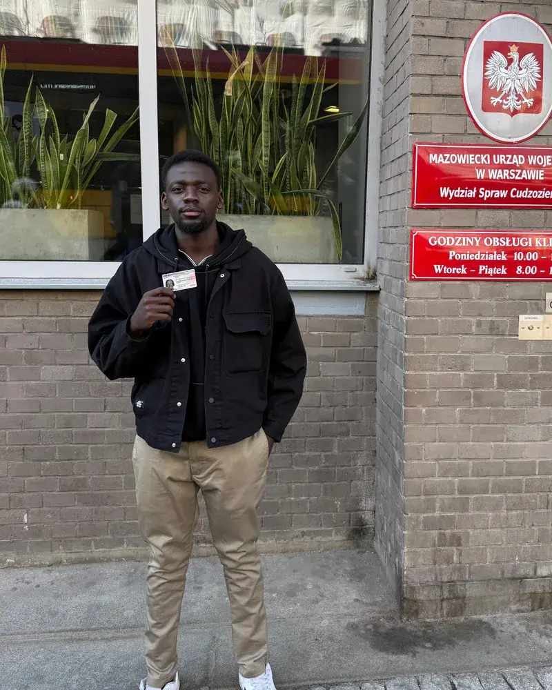 A client holding a new Polish residence card outside the immigration office in Warsaw